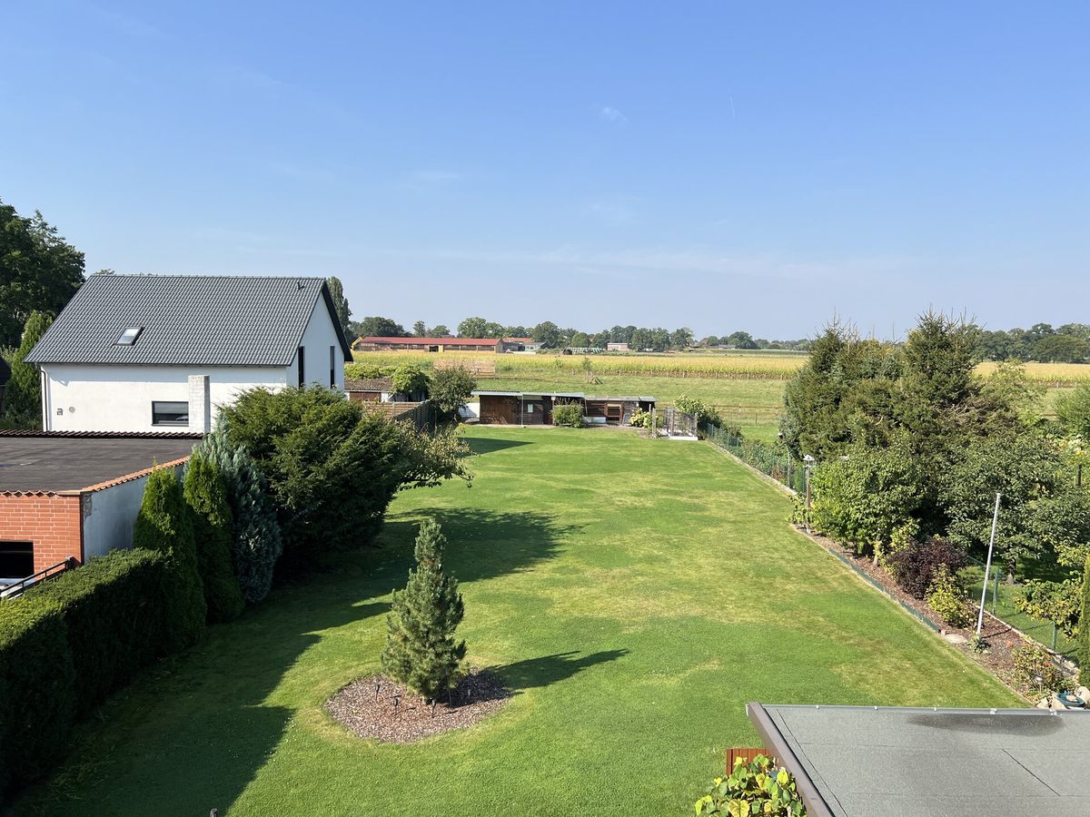 Blick über den weitläufigen Garten eines Zweifamilienhauses in Garbsen mit Feldern im Hintergrund