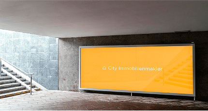 Orangefarbene Werbetafel mit Logo und Schriftzug 'City Immobilienmakler' in einer Unterführung