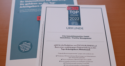 Auszeichnungsurkunde Top Arbeitgeber Mittelstand liegt auf einem Holztisch