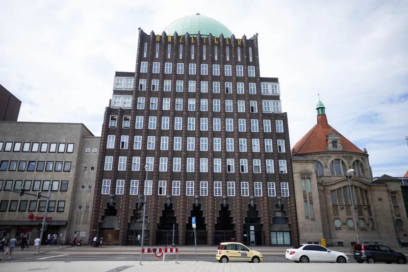 Historisches Backstein-Hochhaus mit grüner Kuppel über einer Straßenkreuzung
