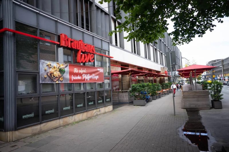 Restaurantfassade 'Brauhaus Live' mit roter Leuchtschrift und Straßencafé