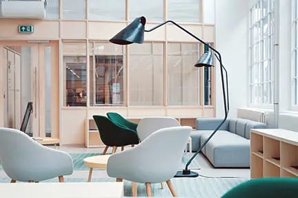 Offener Büro-Loungebereich mit Sesseln, Stehlampe und Glaswänden